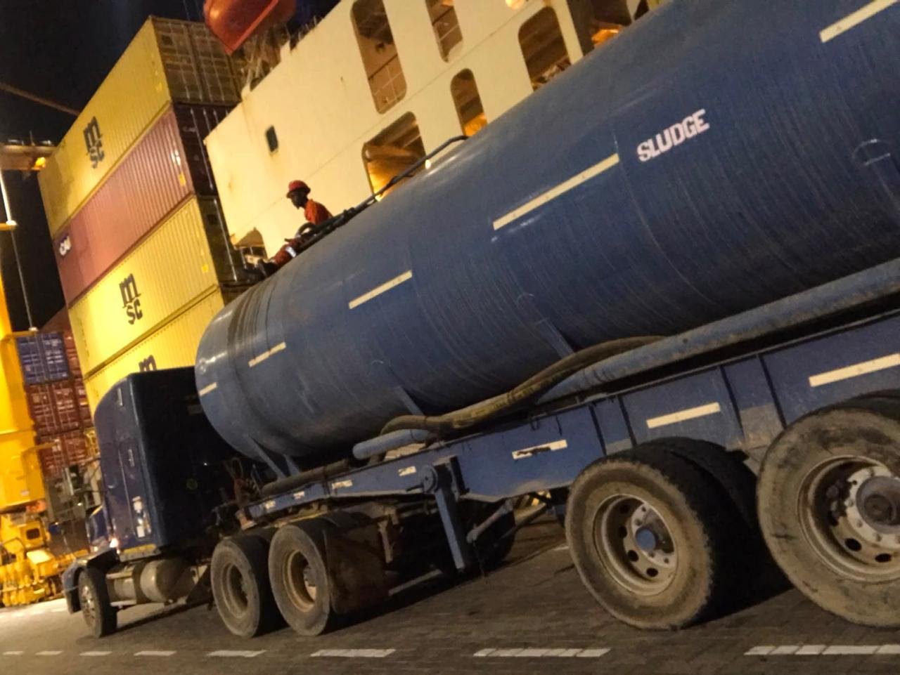 Tila water tanker next to containers in the port